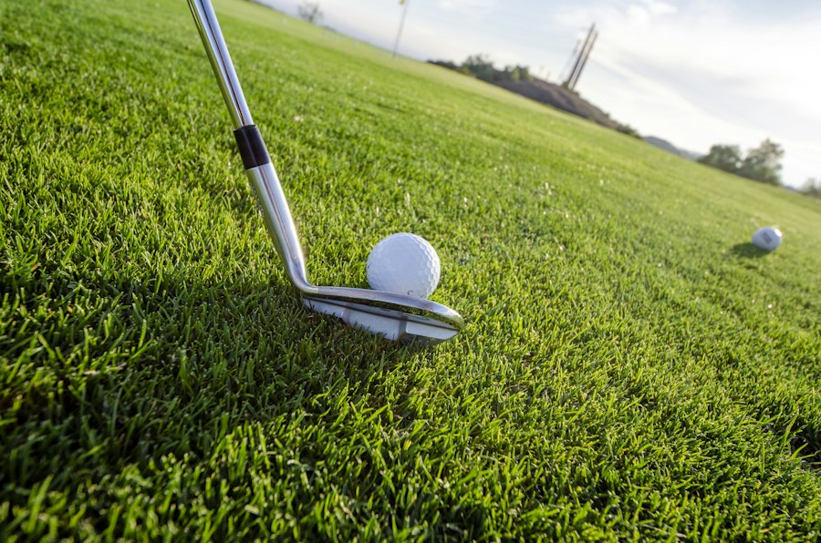 Iron address behind a golf ball on short grass