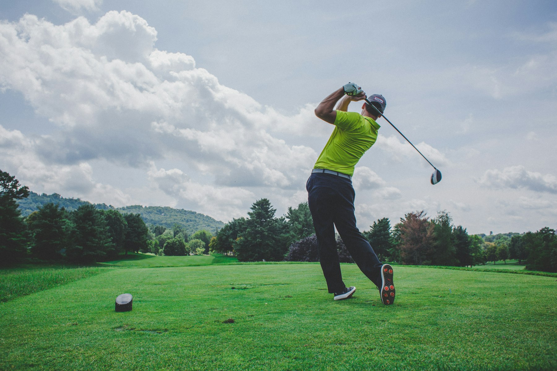 Golfer at the top of the backswing on a tree-lined fairway